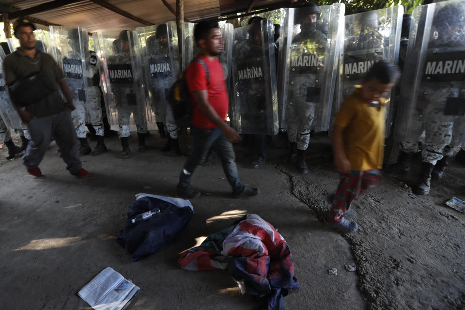 Mexican National Guards stand by as detained migrants walk past, near Tapachula, Mexico, Thursday Jan. 23, 2020. Hundreds of Central American migrants crossed the Suchiate River into Mexico from Guatemala Thursday after a days-long standoff with security forces. (AP Photo/Marco Ugarte)