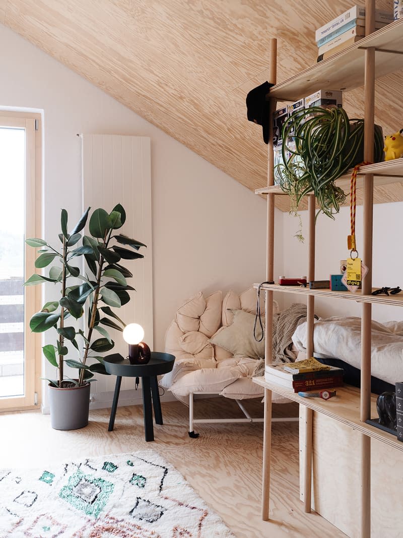 Potted plant and accent table in corner seating area of neutral room with wood ceiling.