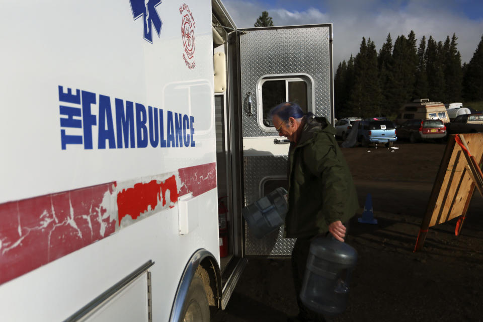 Oregon EMT Thomas Curotto carries empty water jugs to his "fambulance" in the parking lot of the Rainbow Gathering on Friday, July 2, 2021, in the Carson National Forest, outside of Taos, N.M. More than 2,000 people have made the trek into the mountains of northern New Mexico as part of an annual counterculture gathering of the so-called Rainbow Family. While past congregations on national forest lands elsewhere have drawn as many as 20,000 people, this year’s festival appears to be more reserved. Members. (AP Photo/Cedar Attanasio)