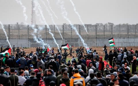 Tear gas canisters fall amongst Palestinian protesters during the demonstration - Credit: &nbsp;MAHMUD HAMS/AFP