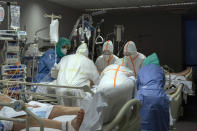 In this photo taken on Friday, March 27, 2020, healthcare workers assist a patience at one of the intensive care units (ICU) at German Trias i Pujol hospital in Badalona, in the Barcelona province, Spain. The new coronavirus causes mild or moderate symptoms for most people, but for some, especially older adults and people with existing health problems, it can cause more severe illness or death. (AP Photo/Anna Surinyach)