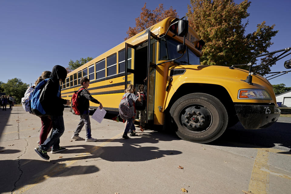 Students board a bus after classes at Highland Elementary School in Columbus, Kan., on Monday, Oct. 17, 2022. Third graders in the tiny 900-student Columbus school district have fought to catch up on reading in the wake of COVID-19 disruptions. (AP Photo/Charlie Riedel)