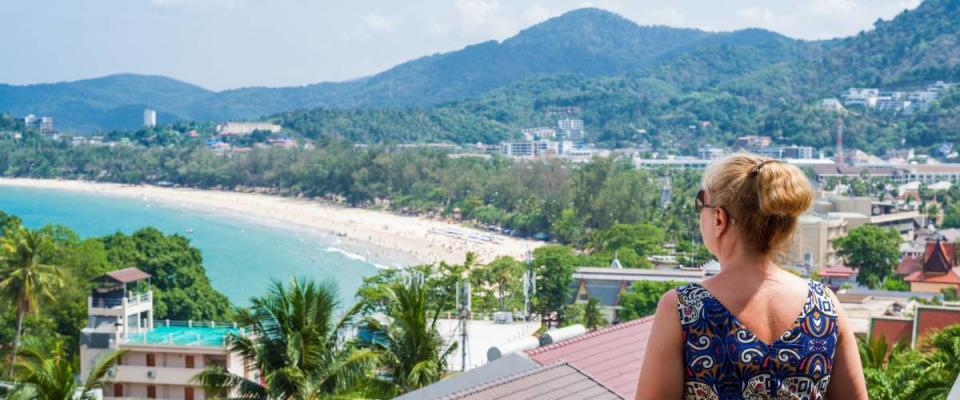 Woman enjoying the views over Kata beach from the hotel balcony. Phuket, Thailand