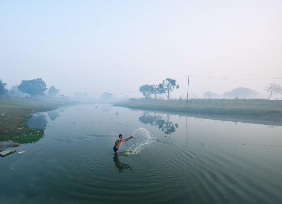 A man baths during a cold and foggy morning in New Delhi