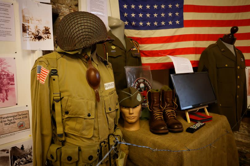 Old uniforms, boots, hats, American flag etc - artefacts and memorabilia on table and beside at exhibition about the 508th Infantry Regiment of the American 82nd Airborne Division at the Wollaton Village Dovecote Museum in Dovecote Drive, Wollaton, Nottingham.