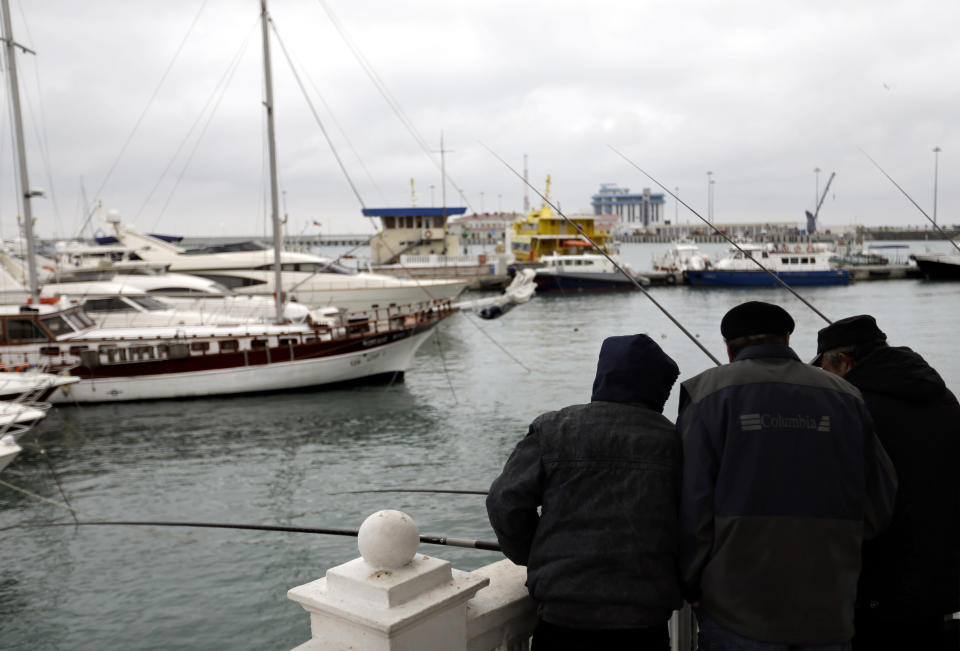 Fisherman huddle together while casting off a boardwalk in a seaport along the Black Sea, Wednesday, Jan. 29, 2014, in Sochi, Russia, home of the upcoming 2014 Winter Olympics. (AP Photo/David Goldman)