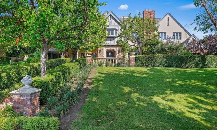 A Tudor-style home sits before an expanse of grassy lawn.