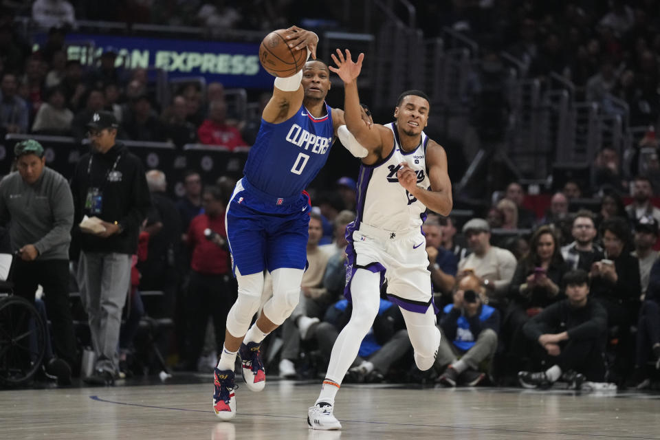 Los Angeles Clippers guard Russell Westbrook (0) and Sacramento Kings forward Keegan Murray (13) reach for a loose ball during the first half of an NBA basketball game in Los Angeles, Tuesday, Dec. 12, 2023. (AP Photo/Ashley Landis)