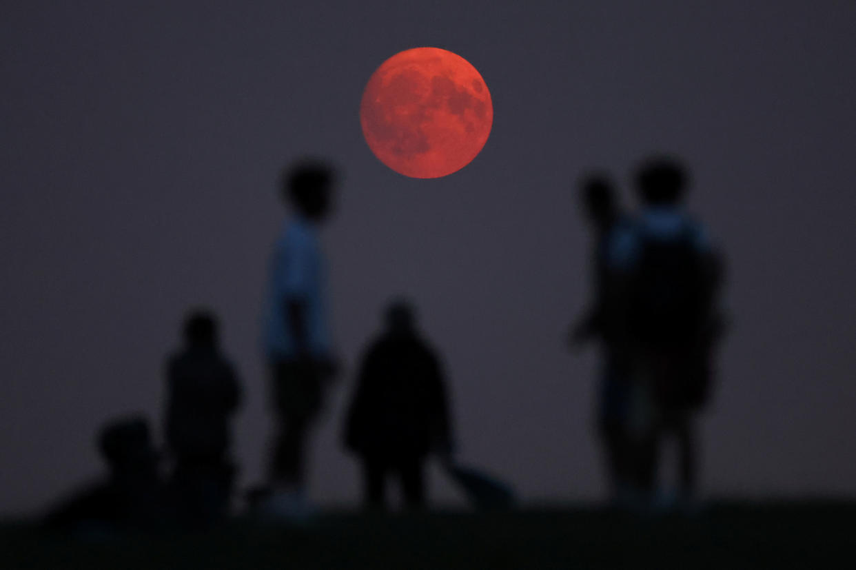 People at Parliament Hill in London view the supermoon as it rises.