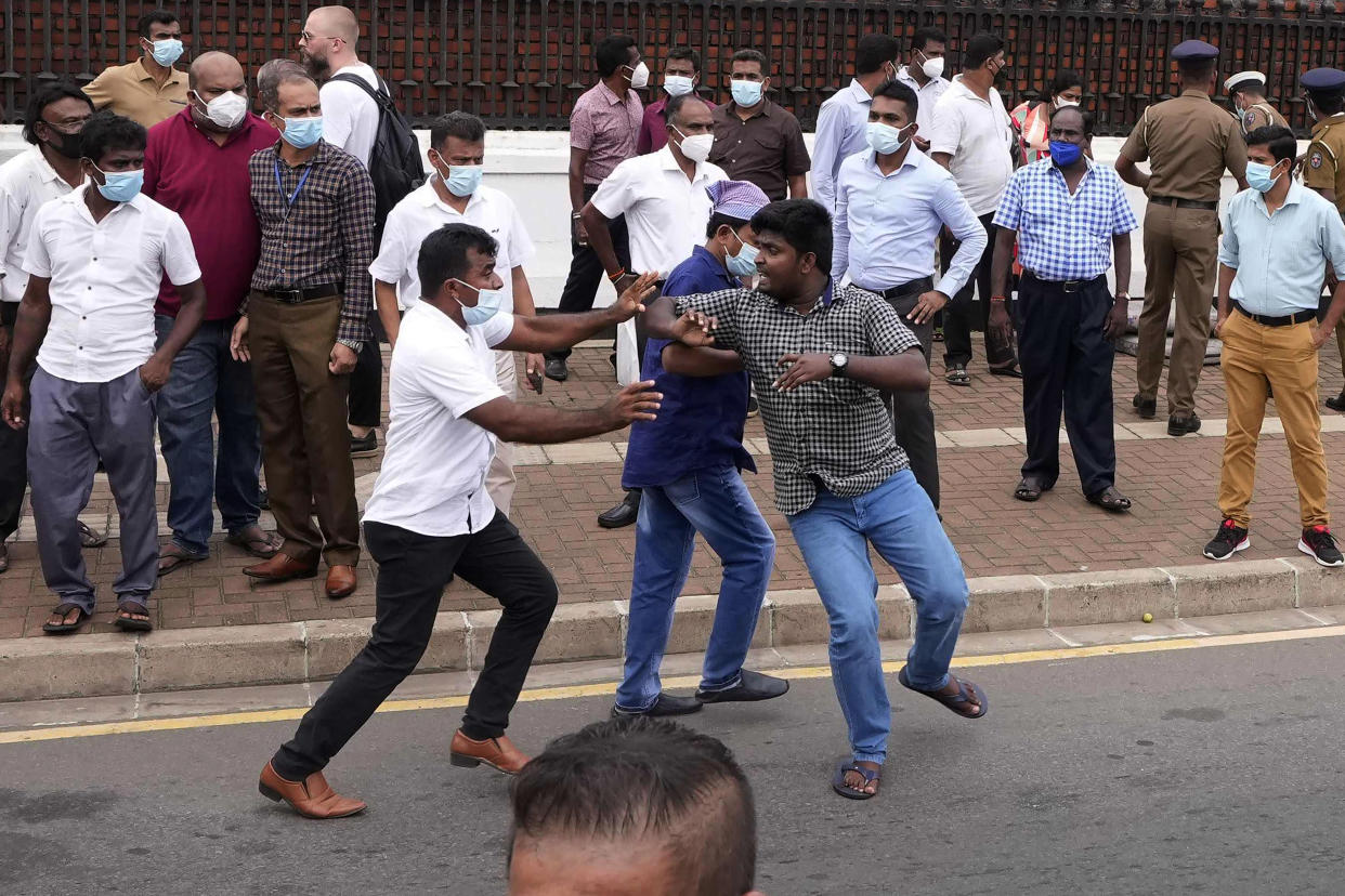 A Sri Lankan government supporter, center left in white shirt, attacks an anti-government protester during clashes outside prime minister's residence outside prime minister's residence in Colombo, Sri Lanka, Monday, May 9, 2022. Authorities deployed armed troops in the capital Colombo on Monday hours after government supporters attacked protesters who have been camped outside the offices of the country's president and prime minster, as trade unions began a “Week of Protests” demanding the government change and its president to step down over the country’s worst economic crisis in memory. (AP Photo/Eranga Jayawardena)