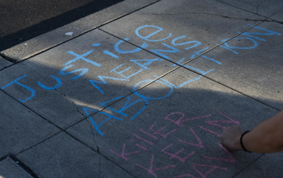 A protester writes a message in favor of police abolition with sidewalk chalk as people rally after body camera footage was released of a Seattle police officer joking about the death of Jaahnavi Kandula, a 23-year-old woman hit and killed in January by officer Kevin Dave in a police cruiser, Thursday, Sept. 14, 2023, in Seattle. (AP Photo/Lindsey Wasson)