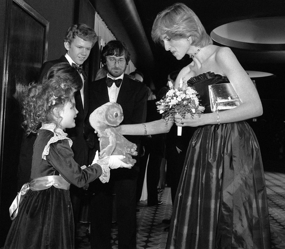 Seven year old American actress Drew Barrymore (left), star of the movie ET, presents the Princess of Wales with a cuddly toy version of the film's main character, at the Empire cinema,  in Leicester Square, London.  * Left from Drew, one of the film's stars Henry Thomas (obscured), Robert MacNaughton, and the film's director Steven Spielberg (with beard).   (Photo by PA Images via Getty Images)