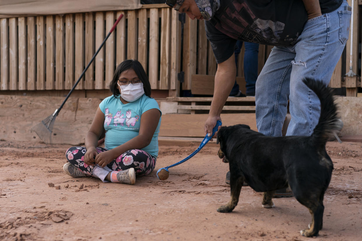 Annabelle Dinehdeal, 8, watches as her father Eugene Dinehdeal, plays ball with their dog Wally on their family compound in Tuba City, Arizona, on the Navajo reservation. The family has been devastated by COVID-19. The Navajo reservation has some of the highest rates of coronavirus in the country. (Photo: ASSOCIATED PRESS)