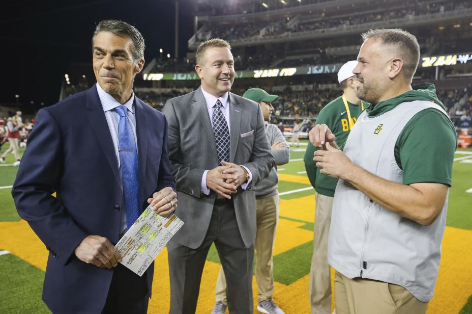 ESPN's Chris Fowler, left, and Kirk Herbstreit, center, talk with Baylor head coach Matt Rhule prior to an NCAA college football game against Oklahoma in Waco, Texas, Saturday, Nov. 16, 2019. The ESPN “College GameDay” analyst Herbstreit and the network's broadcaster Fowler announced Thursday, Feb. 22, 2024, on social media they will be voices in EA Sports' upcoming college football video game. (AP Photo/Ray Carlin, File)