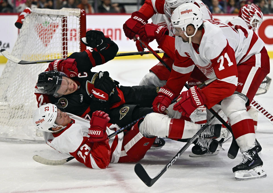 Detroit Red Wings left wing Lucas Raymond (23) and Ottawa Senators left wing Brady Tkachuk (7) fall to the ice as Red Wings Dylan Larkin (71) looks on during the first period of an NHL hockey action in Ottawa, Ontario, Saturday, Oct. 21, 2023. (Justin Tang/The Canadian Press via AP)