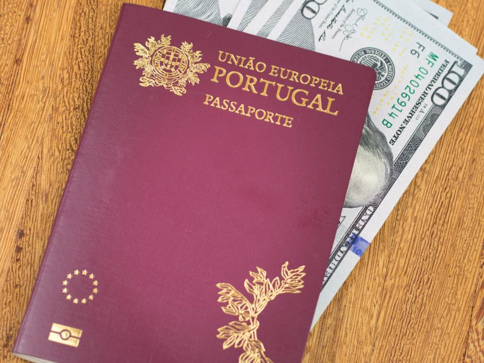 Portuguese passport (Translation "European Union Portugal passport") and one hundred dollar banknotes wooden background