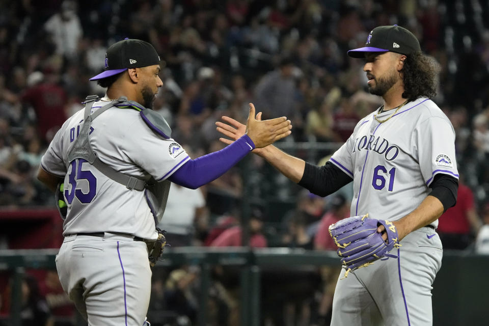 Colorado Rockies catcher Elias Diaz (35) and pitcher Justin Lawrence celebrate after defeating the Arizona Diamondbacks during a baseball game, Saturday, March 30, 2024, in Phoenix. (AP Photo/Rick Scuteri)