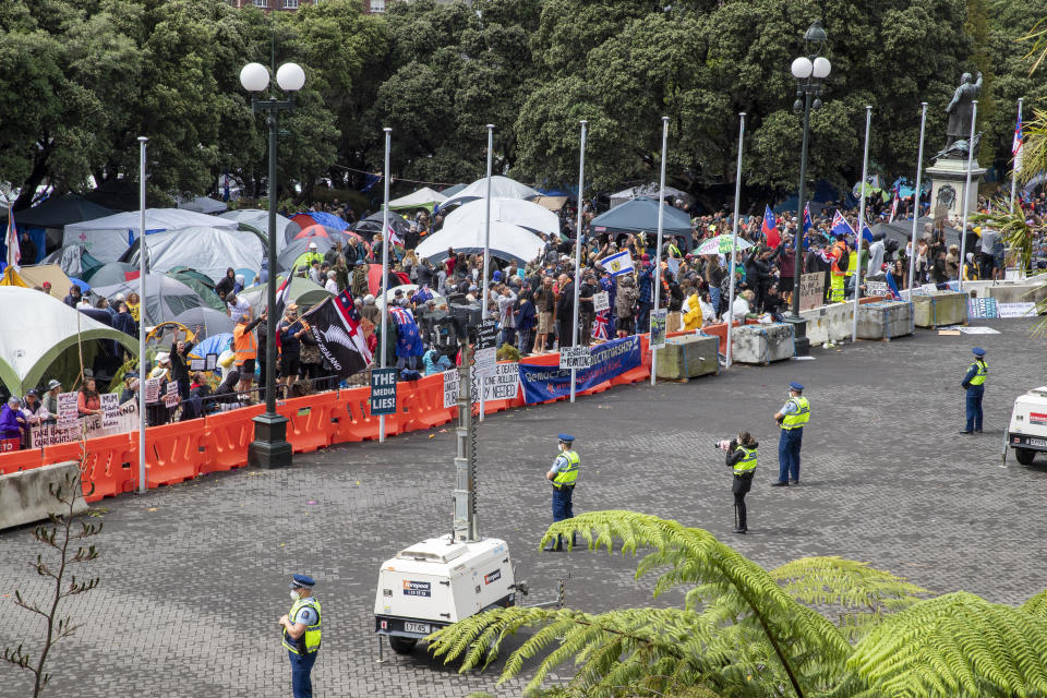 Police keep a watch as people who oppose vaccine mandates gather near Parliament in  Wellington, New Zealand Monday, Feb. 14, 2022. The protesters are not planning to leave any time soon after they drove in convoys from around the country nearly a week ago, setting up tents on Parliament's grounds and blocking surrounding streets with their cars and trucks.  / Credit: Mark Mitchell/New Zealand Herald via AP