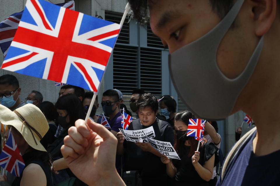 FILE - In this Oct. 1, 2019, file photo, a group of Hong Kong residents waving U.K. flags demonstrate requesting right to British residency outside the British embassy in Hong Kong. Hong Kong’s government says it will ban all passenger flights from the U.K. starting Thursday, July 1, 2021, as it seeks to curb the spread of new variants of the coronavirus. The ban comes amid heightened tensions between the U.K. and China over semi-autonomous Hong Kong, which was a British colony until it was handed over to China in 1997. (AP Photo/Gemunu Amarasinghe, File)