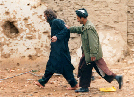 FILE PHOTO: U.S.-born John Walker Lindh (L) is led away by a Northern Alliance soldier after he was captured among al Qaeda and Taliban prisoners following an uprising at the Fort Qali-i-Janghi prison near Mazar-i-Sharif December 1, 2001 REUTERS/STR/File Photo