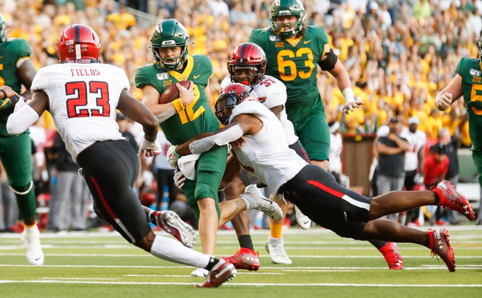 Baylor Bears quarterback Charlie Brewer (12) is dragged down by Texas Tech Red Raiders linebacker Jordyn Brooks (1) during the second half at McLane Stadium in 2019.