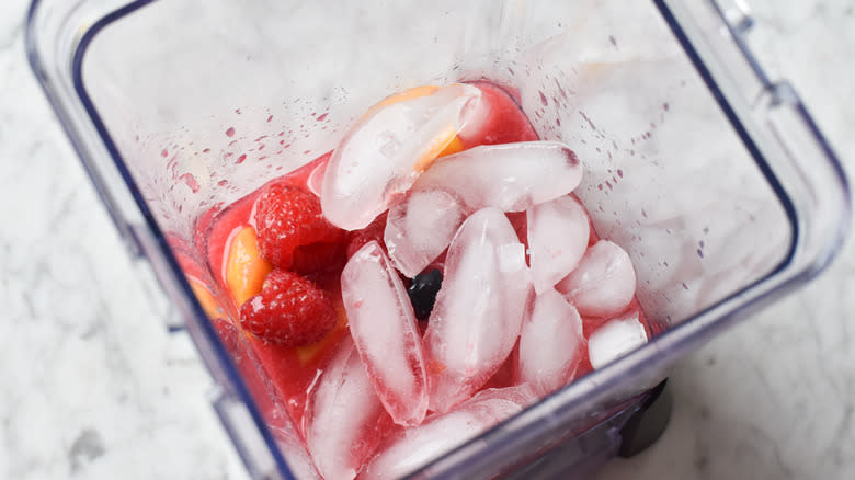 adding bananas, raspberries, and ice to blender