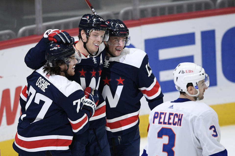 Washington Capitals defenseman John Carlson, center, celebrates his goal with right wing T.J. Oshie (77) and left wing Jakub Vrana (13) during the first period of an NHL hockey game, as New York Islanders defenseman Adam Pelech (3) skates by, Tuesday, Jan. 26, 2021, in Washington. (AP Photo/Nick Wass)