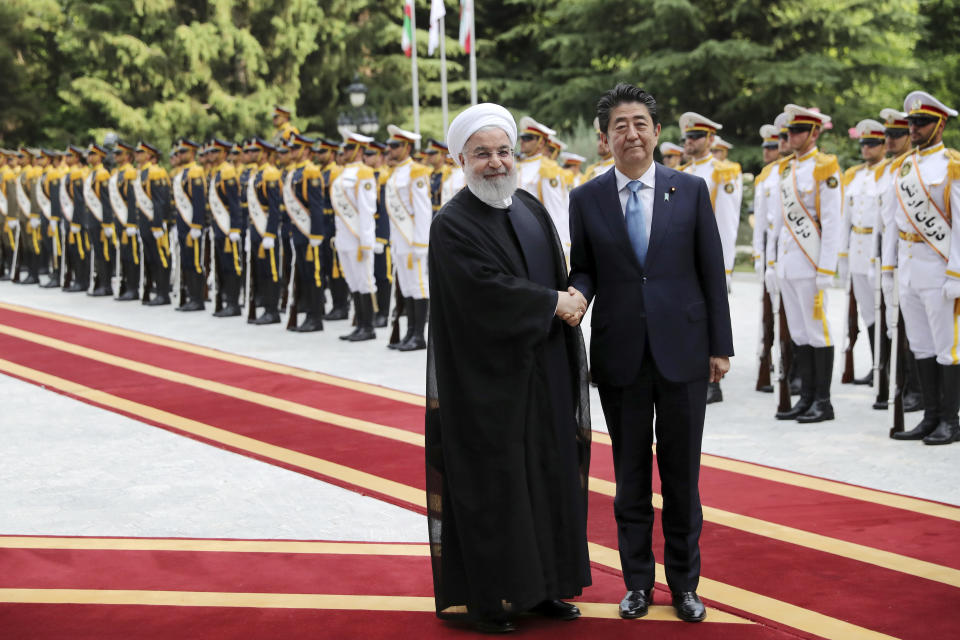 Japanese Prime Minister Shinzo Abe, center, shakes hands for the cameras with Iranian President Hassan Rouhani, during the official arrival ceremony, at the Saadabad Palace in Tehran, Iran, Wednesday, June 12, 2019. The Japanese leader is in Tehran on a mission to calm tensions between the U.S. and Iran. (AP Photo/Ebrahim Noroozi)