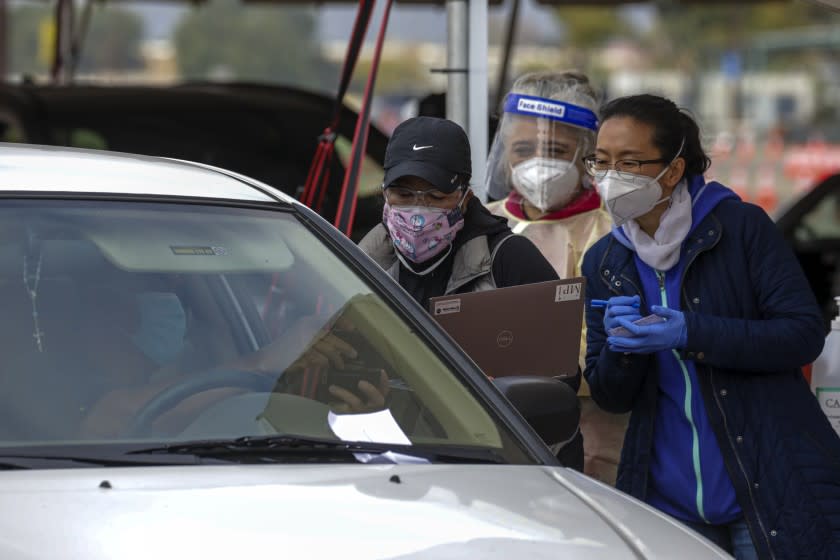 Pomona, CA - February 10: Department of health workers Donna Lee, left, nurse Maria Pantoja and Long Liang verify the information before administering the second dose of COVID-19 vaccine to a person at Los Angeles County run location Pomona Fairplex on Wednesday, Feb. 10, 2021 in Pomona, CA.(Irfan Khan / Los Angeles Times)