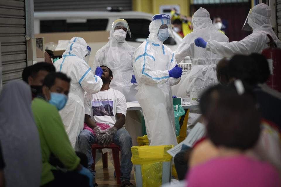 A health worker collects sample for coronavirus testing from a worker at a locked down wet market as one of its traders tested positive for COVID-19 in Petaling Jaya, Malaysia, Tuesday, April 28, 2020. The Malaysian government issued a restricted movement order to the public till April 28, to help curb the spread of the new coronavirus. (AP Photo/Vincent Thian)