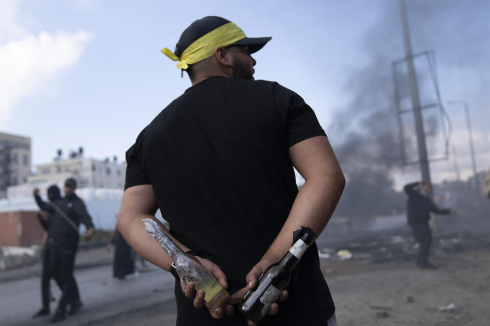 A Palestinian protester carries Molotov cocktails during clashes with Israeli border police following a protest against Israeli airstrikes on Gaza, in the West Bank city of Ramallah, Wednesday, Oct. 18, 2023. (AP Photo/Nasser Nasser)
