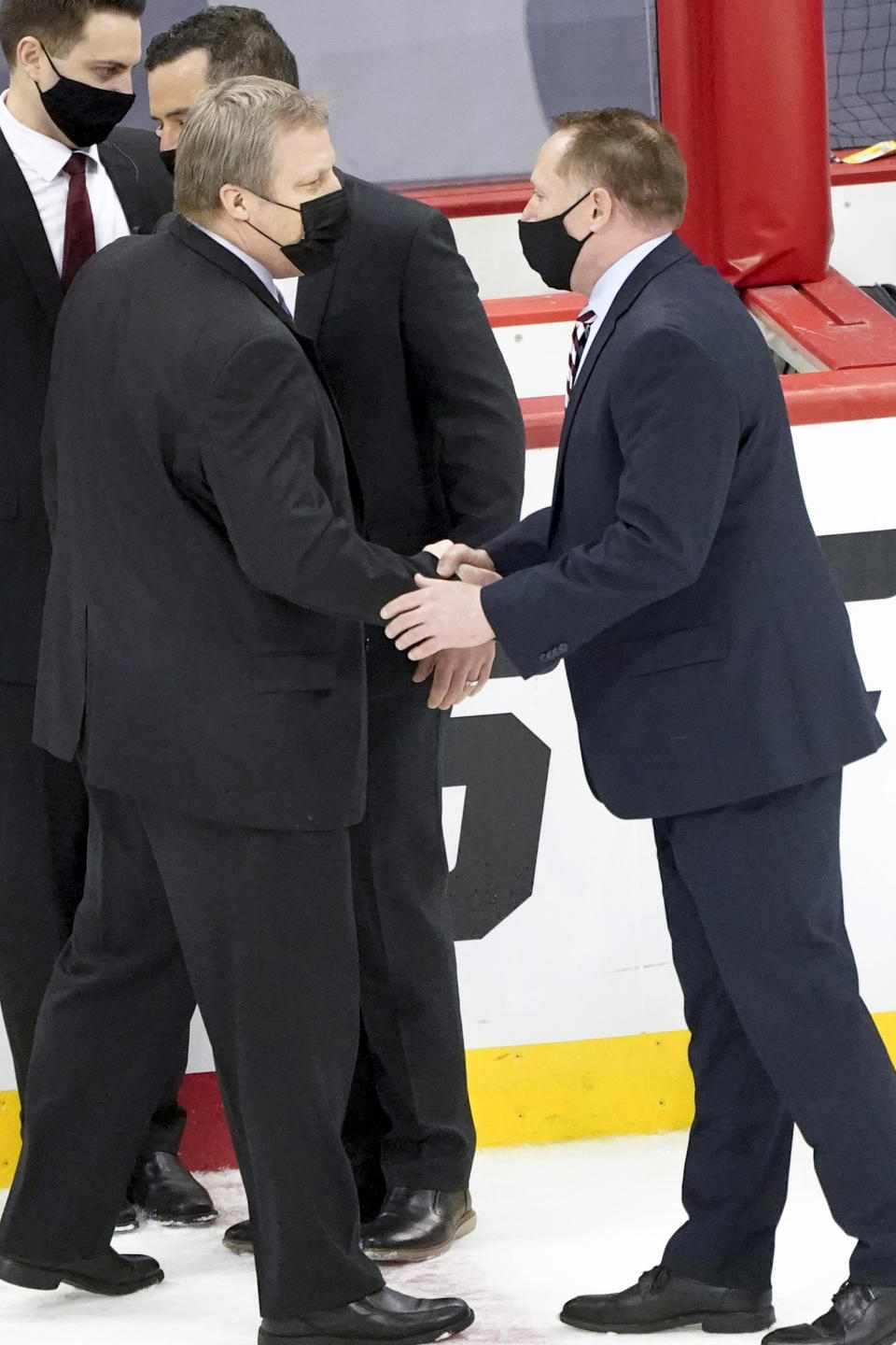 Minnesota Duluth coach Scott Alan Sandelin, left, greets Massachusetts coach Greg Carvel after an NCAA men's Frozen Four hockey semifinal in Pittsburgh, early Friday, April 9, 2021. Massachusetts won 3-2 and will face St. Cloud State in the championship game Saturday. (AP Photo/Keith Srakocic)