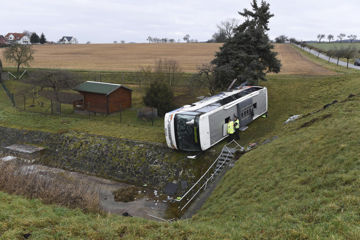 Police officers looks into a school bus that has crashed in Berka Vor Dem Hainich, near Eisenach, Germany, Thursday, Jan. 23, 2020. German media reported that two children died in a school bus crash in the central state of Thuringia early Thursday. Public broadcaster MDR reported that 20 children and the bus driver were injured in the crash in Berka, about 260 kilometers (160 miles) southwest of Berlin. (Swen Pfoertner/dpa via AP)