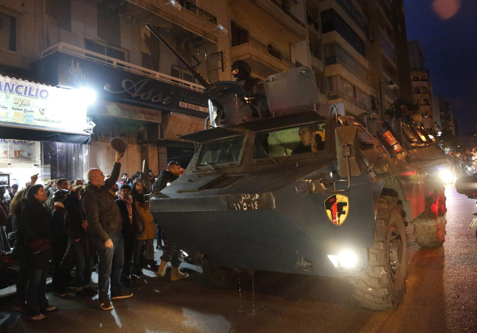 A police armored personnel carrier passes next of anti-government protesters outside police headquarters, as they demand the release of those taken into custody the night before, in Beirut, Lebanon, Wednesday, Jan. 15, 2020. Lebanese security forces arrested 59 people, the police said Wednesday, following clashes overnight outside the central bank as angry protesters vented their fury against the country's ruling elite and the worsening financial crisis. (AP Photo/Hussein Malla)