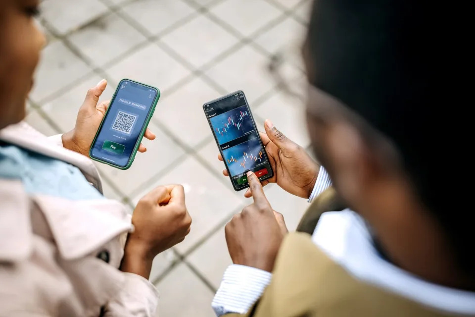 Two people checking charts on their phones.