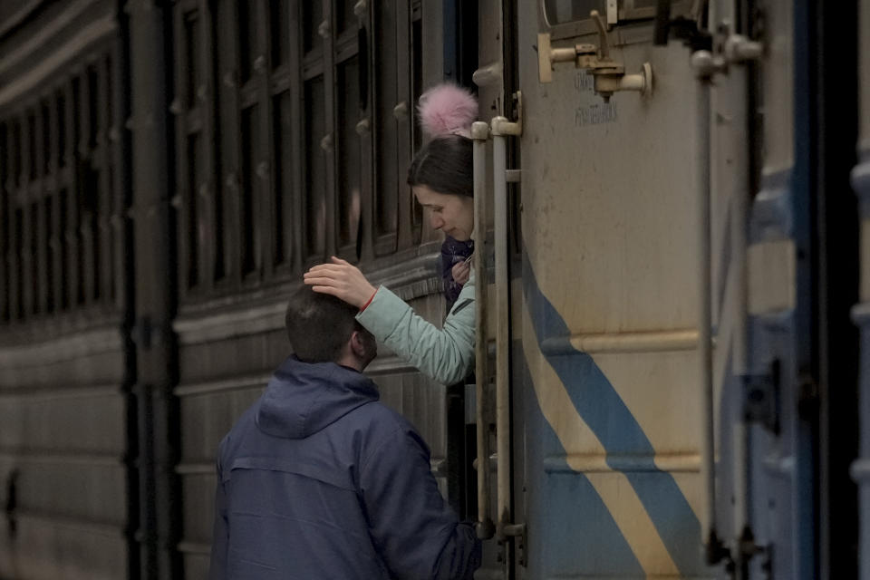 A woman holding a child on a Lviv bound train bids goodbye to a man in Kyiv, Ukraine, Saturday, March 12, 2022. Fighting raged in the outskirts of Ukraine's capital, Kyiv, and Russia kept up its bombardment of other resisting cities. (AP Photo/Vadim Ghirda)