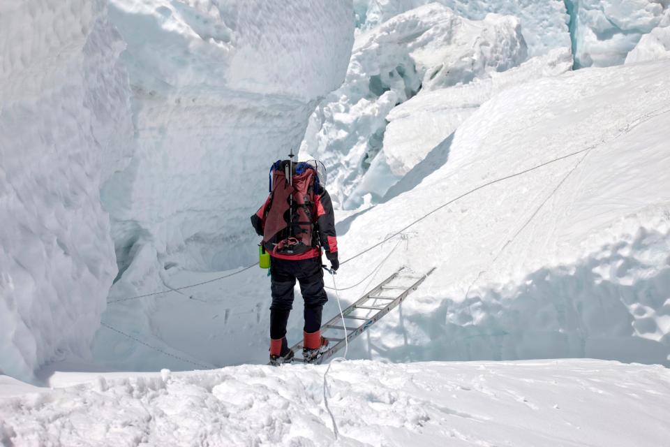 A Mt. Everest cimber prepares to cross a crevasse in the Khumbu Icefall
