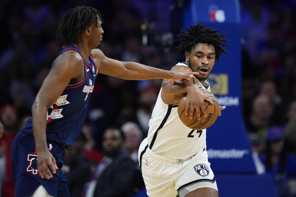 Brooklyn Nets' Cam Thomas, right, and Philadelphia 76ers' Tyrese Maxey reach for a loose ball during the first half of an NBA basketball game, Saturday, Feb. 3, 2024, in Philadelphia. (AP Photo/Matt Slocum)