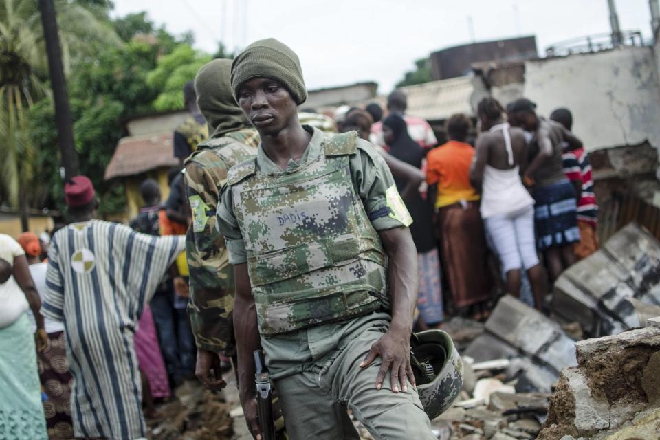 Soldiers stand on the remains of a house that was burnt down during pre-election communal violence in the Taouyah neighbourhood of Guinea's capital Conakry