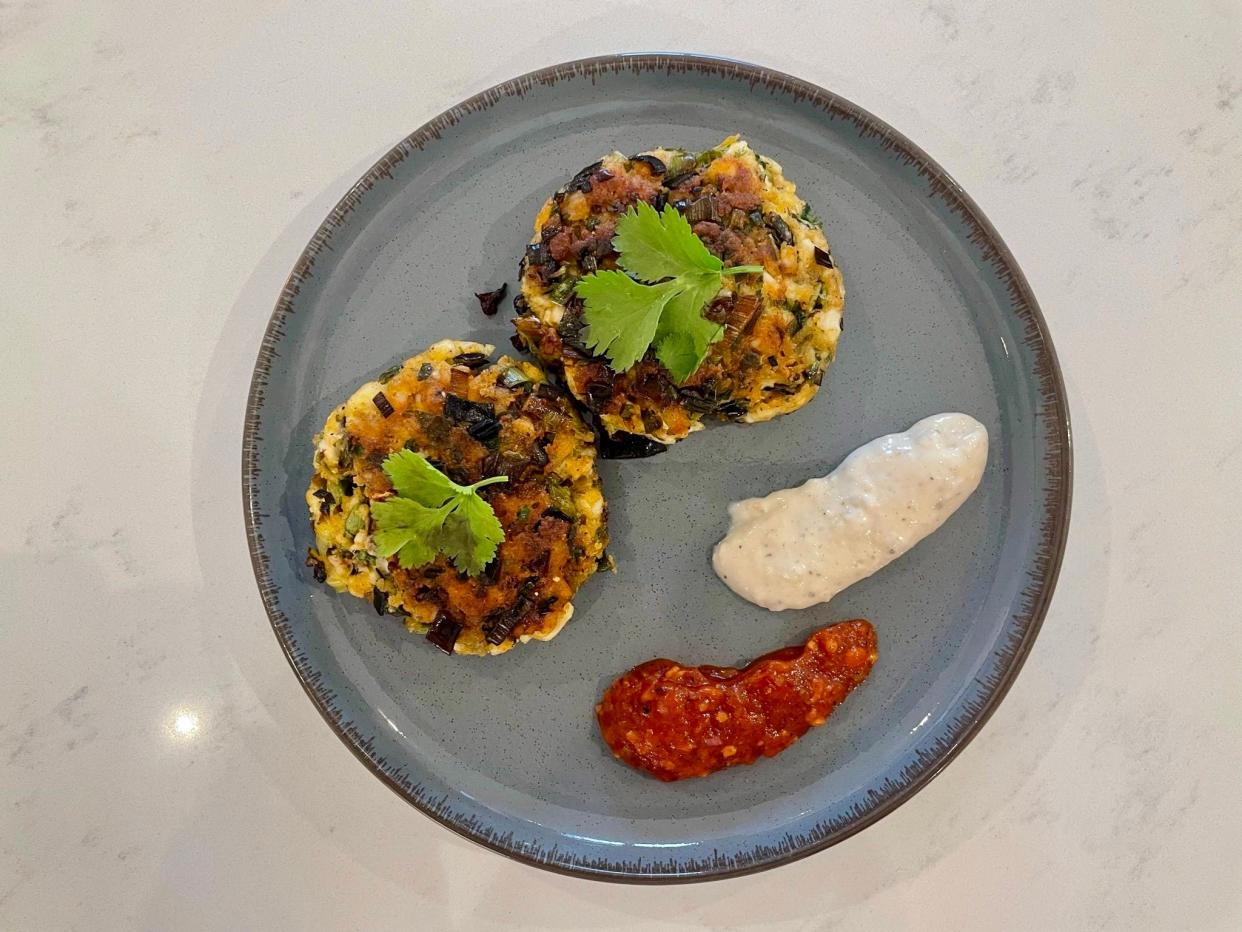 Fishcakes on plate with garnish and garlic mayo and salsa on the side.