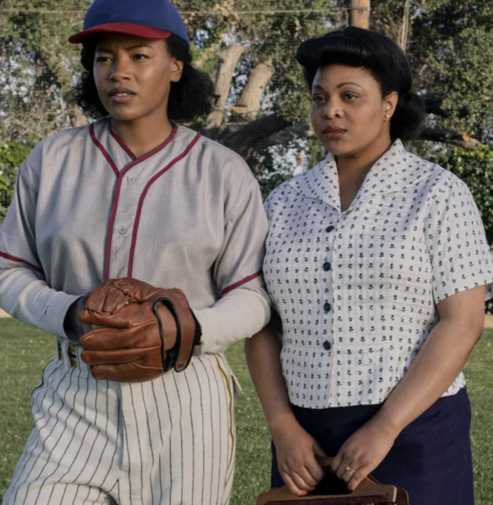 A softball player and another woman look on