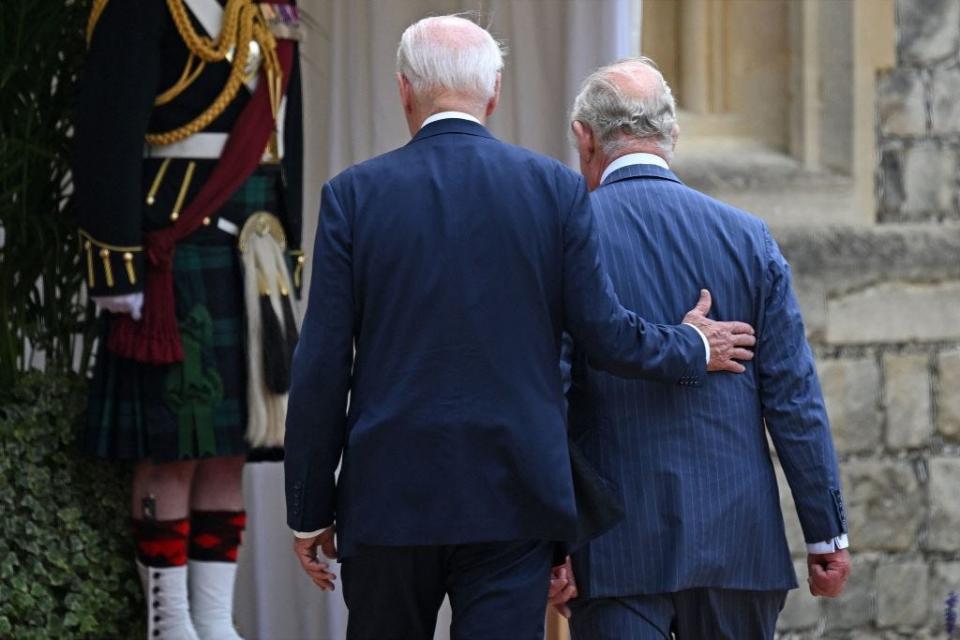 Joe Biden places a hand on King Charles' back