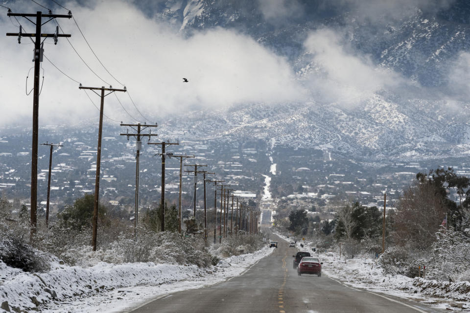 Cars roll down Oasis Road following a fresh snowfall in Pinon Hills Calif., Thursday, Feb. 21, 2019. (James Quigg/The Daily Press via AP)