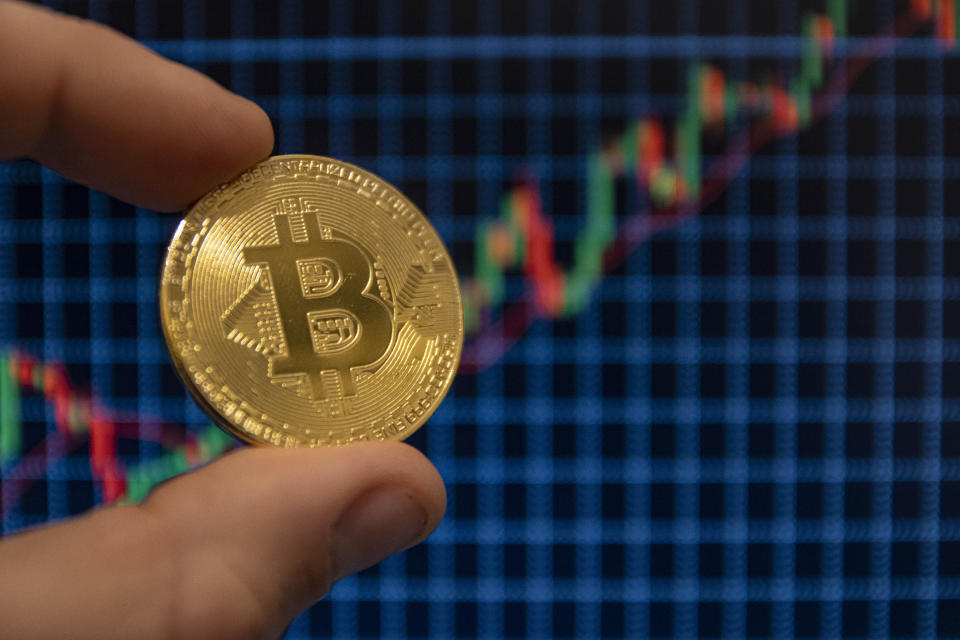 NETHERLANDS - 2020/12/22: In this photo illustration, the Bitcoin golden cryptocurrency commemorative coin seen displayed in front of uptrend graph lines. (Photo Illustration by Nik Oiko/SOPA Images/LightRocket via Getty Images)