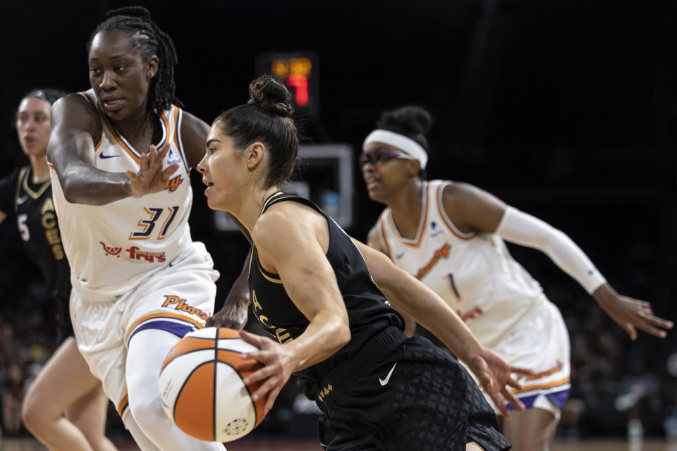 Las Vegas Aces guard Kelsey Plum, center, drives around Phoenix Mercury center Tina Charles (31) during the first half of a WNBA basketball game, Saturday, May 21, 2022, in Las Vegas. Mercury guard Diamond DeShields, right, looks on. (AP Photo/Ellen Schmidt)