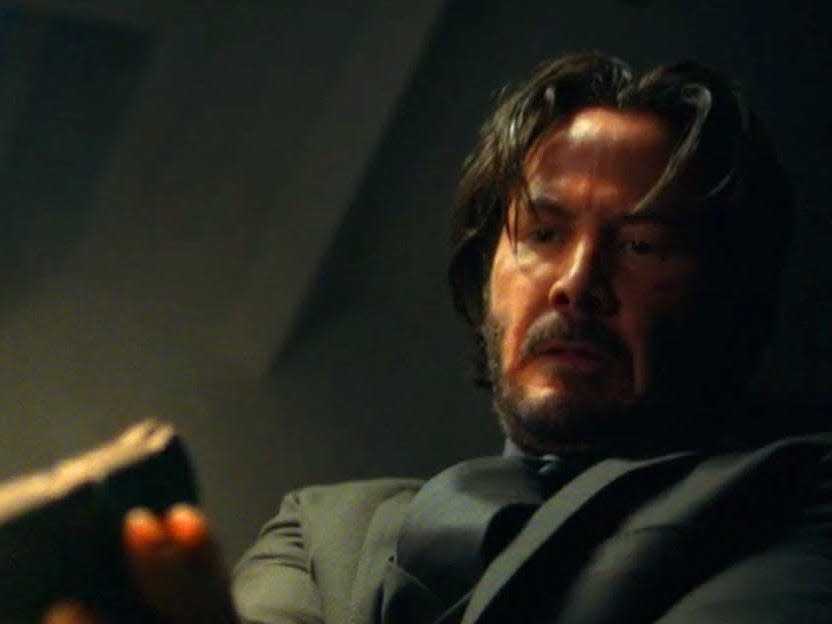 Keanu Reeves as John Wick shooting someone off-camera.
