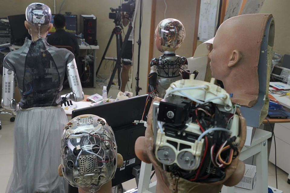 The head of Sophia, left, and other robotics show the inside content visually through the transparent skull at Hanson Robotics studio in Hong Kong on March 29, 2021. Sophia is a robot of many talents — she speaks, jokes, sings and even makes art. In March, she caused a stir in the art world when a digital work she created as part of a collaboration was sold at an auction for $688,888 in the form of a non-fungible token (NFT). (AP Photo/Vincent Yu)