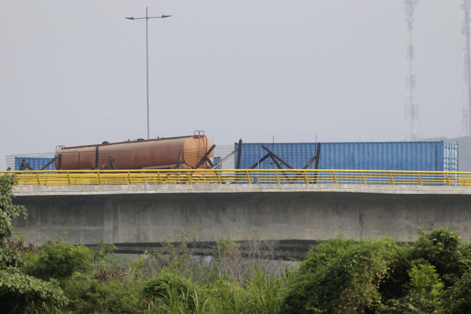 A fuel tanker, cargo trailers and makeshift fencing are used as barricades by Venezuelan authorities attempting to block humanitarian aid entering from Colombia on the Tienditas International Bridge that links the two countries as seen from the outskirts of Cucuta, Colombia, Wednesday, Feb. 6, 2019. Immigration authorities say the Venezuelan National Guard built the roadblock a day earlier. (AP Photo/Fernando Vergara)