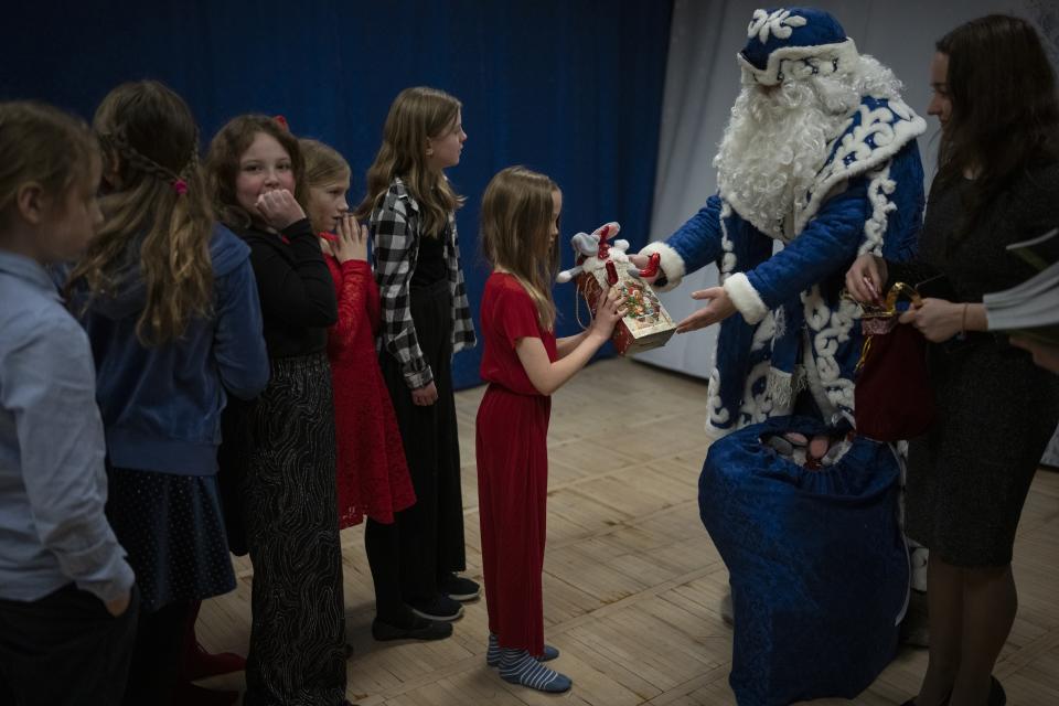 Members of Polargospel, the children's choir at the only church in Svalbard, receive gifts from a Barentsburg teacher acting as Ded Moroz, the Slavic equivalent of Santa in Barentsburg, Norway, Saturday, Jan. 7, 2023. The children's choir traveled three hours each way by boat to mark Orthodox Christmas with the 40 children in Barentsburg, a village owned by Russia's Arctic mining company in the remote Norwegian territory. (AP Photo/Daniel Cole)