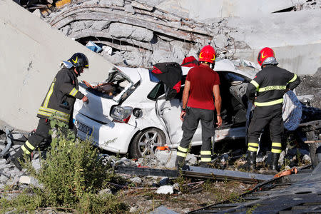 Firefighters inspect a crushed car August 14, 2018. REUTERS/Stefano Rellandini